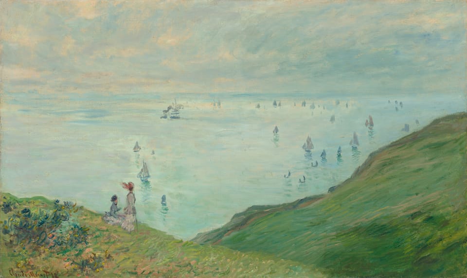 Two women in dresses and hats overlooks cliffs and the sea, which is spotted with sailboats.